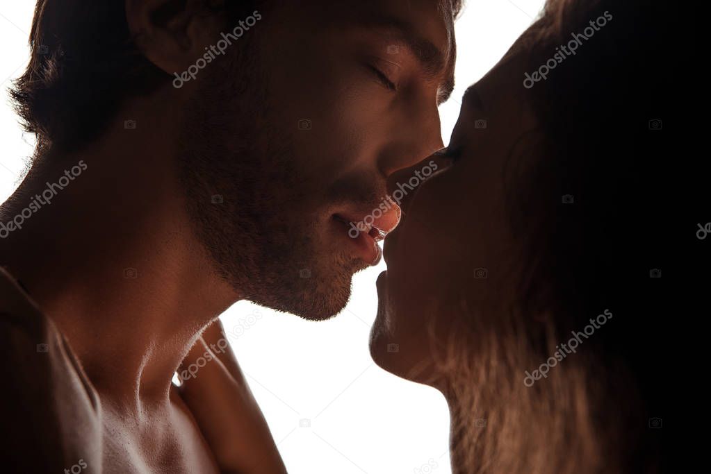 side view of couple kissing while standing face to face, isolated on white