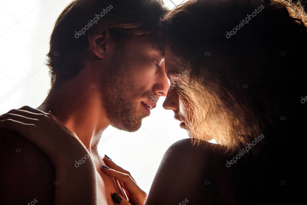 side view of couple kissing while standing face to face, isolated on white