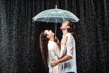 mutlu çift beyaz gömlek siyah izole yağmur damlaları altında şemsiyesi altında ayakta yan görünüm