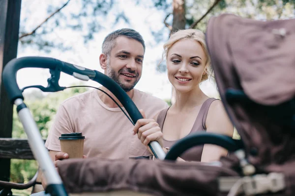 Parents Souriants Assis Sur Banc Près Voiture Bébé Dans Parc — Photo