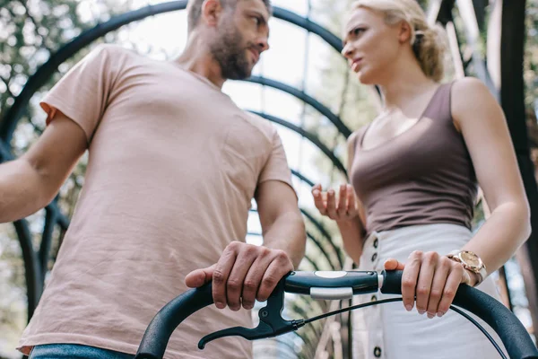 low angle view of angry parents talking near baby carriage in park