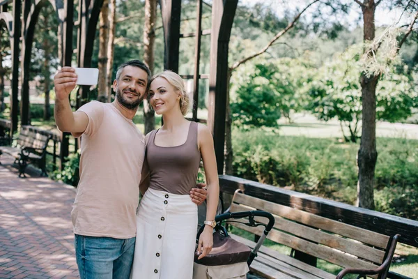 Smiling Couple Taking Selfie Smartphone Baby Carriage Park — Stock Photo, Image