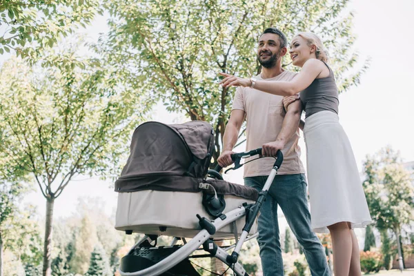 Parents Heureux Marchant Avec Voiture Bébé Dans Parc Femme Pointant — Photo