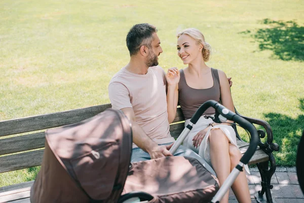 Smiling Parents Sitting Bench Baby Carriage Park Looking Each Other — Stock Photo, Image
