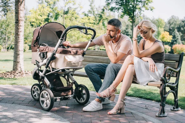 Parents Tristes Assis Sur Banc Près Voiture Bébé Dans Parc — Photo