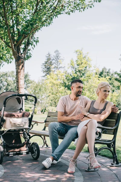 Mann Umarmt Irritierte Frau Auf Bank Neben Kinderwagen Park — Stockfoto