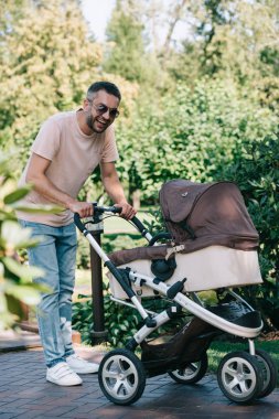 baba bebek arabası park ve kameraya arıyor ile yürüme gülümseyen