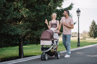 mutlu anne bebek arabası ve dondurma parkta yürüyüş
