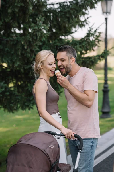 Smiling Husband Feeding Wife Ice Cream Baby Carriage Park — Free Stock Photo