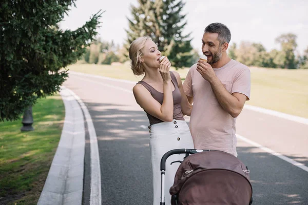 Gelukkige Ouders Eten Van Ijs Buurt Van Kinderwagen Park — Gratis stockfoto