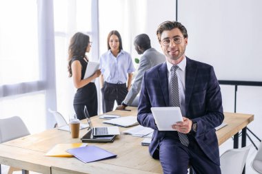 seçici odak tablet ve Office arkasında çok ırklı meslektaşları ile beyaz iş adamı