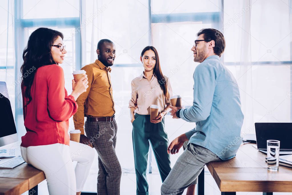interracial business colleagues having conversation during coffee break in office