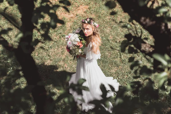 花と屋外カメラ目線の花束を持って美しい若い花嫁のハイアングル  — 無料ストックフォト