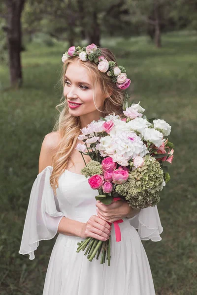 Piękny Uśmiechający Się Młodej Wieniec Kwiatowy Trzymając Bukiet Ślubny Szukasz — Zdjęcie stockowe