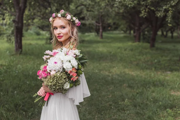 Наречена Квітковому Вінку Весільній Сукні Тримає Букет Квітів Дивиться Камеру — стокове фото