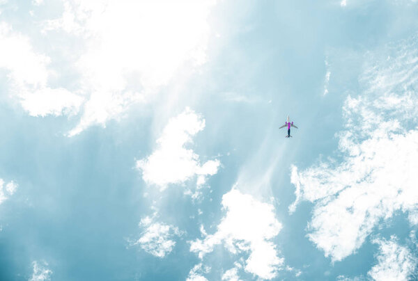 bottom view of airplane flying in blue sky with white clouds