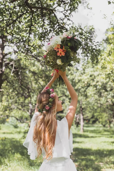 公園でウェディング ブーケを投げる美しい若い花嫁の背面図 — ストック写真