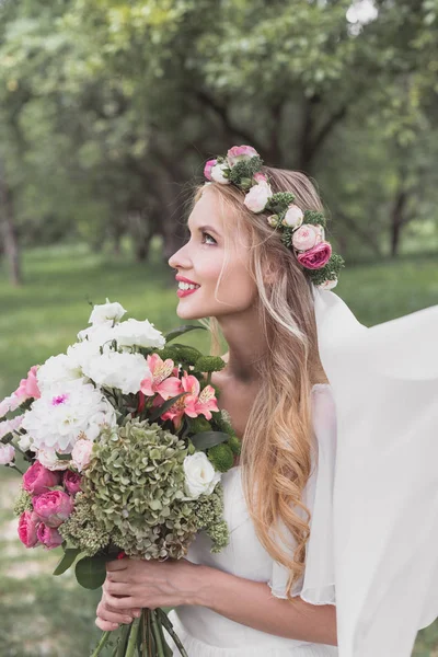 ベール ウェディング ブーケを押しながら見上げる美しい笑顔若い花嫁の側面図 — ストック写真