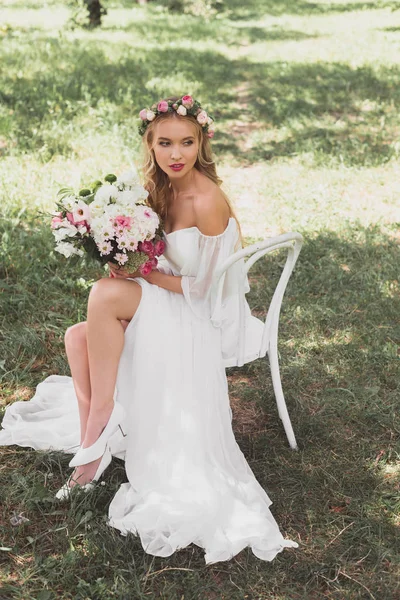 美しい柔らかい若い花嫁ウェディング ブーケを押しながら屋外で椅子に座ってのハイアングル — ストック写真