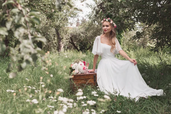 木製のたんすの上に座って 公園に目をそむける美しい笑顔の若い花嫁 — ストック写真