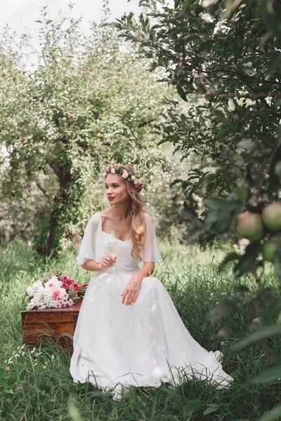 ワインのガラスを保持していると 庭でビンテージの胸の上に座って美しい幸せの若い花嫁 — ストック写真