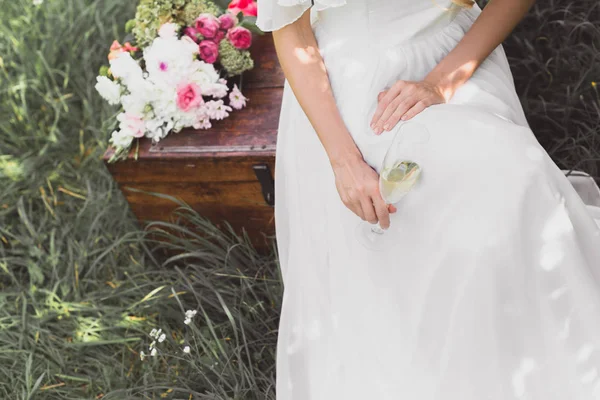 拍摄的新娘拿着酒杯和坐在老式的胸部 — 图库照片