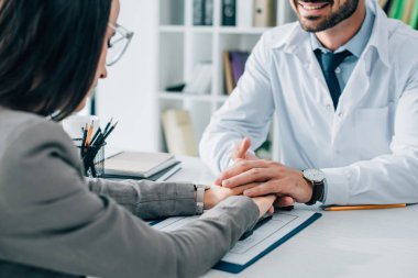 hasta ve gülümseyen Doktor elele sigorta hasar talep formu yukarıda klinikte görüntü kırpılmış