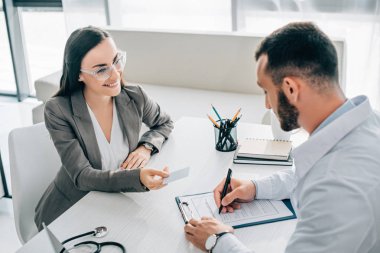 yüksek açı görüntülemek gülümseyen hasta veren kimlik kartının doktor hastane sigorta hasar talep formu doldurmak için