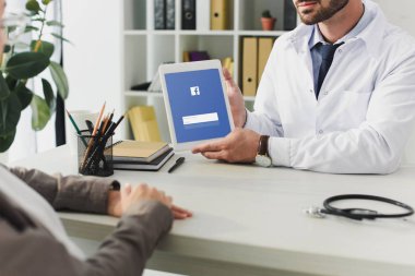 Doktor hastaya Kliniği tablet yüklü facebook sayfası ile gösterilen görüntü kırpılmış