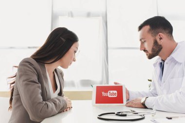 Klinikte hasta tablet yüklü youtube sayfası ile gösterilen doktor 