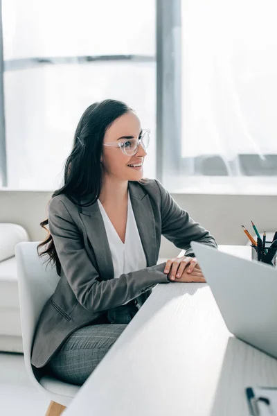 Mujer Negocios Sonriente Sentada Mesa Oficina Mirando Hacia Otro Lado — Foto de stock gratuita