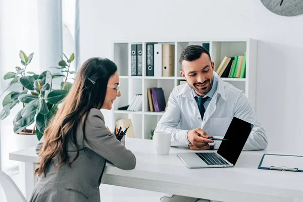 Doctor Feliz Señalando Ordenador Portátil Con Pantalla Blanco Paciente Clínica — Foto de Stock