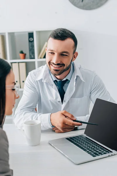 Médico Sorrindo Apontando Laptop Com Tela Branco Para Paciente Clínica — Fotografia de Stock