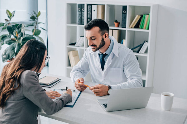 patient signing insurance claim form near general practitioner in clinic