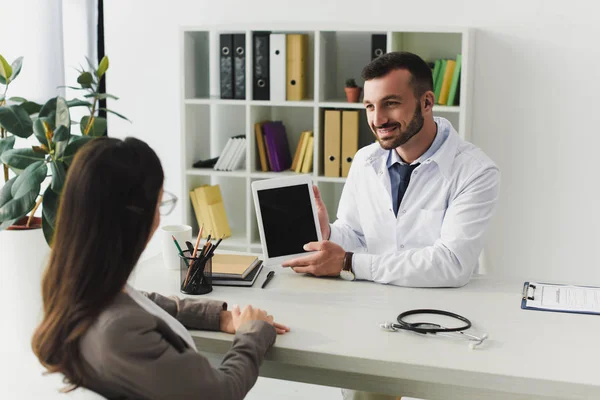 Médecin Souriant Montrant Gadget Patient Avec Écran Blanc Dans Clinique — Photo