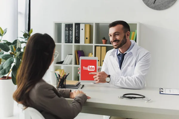 Усміхаючись Лікар Вказуючи Таблетки Завантаженого Youtube Сторінки Клініці — стокове фото
