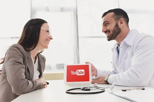 Sonriente Doctor Mostrando Paciente Tableta Con Cargado Youtube Página Clínica — Foto de Stock