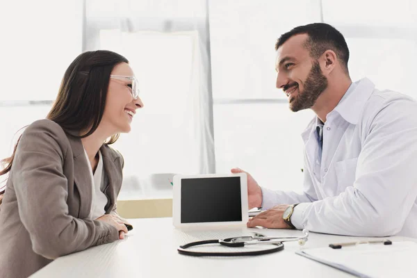 Médico Sonriente Mostrando Tableta Paciente Con Pantalla Blanco Clínica — Foto de Stock