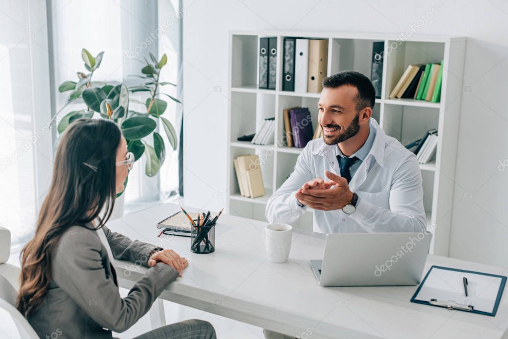 patient and smiling doctor talking in clinic