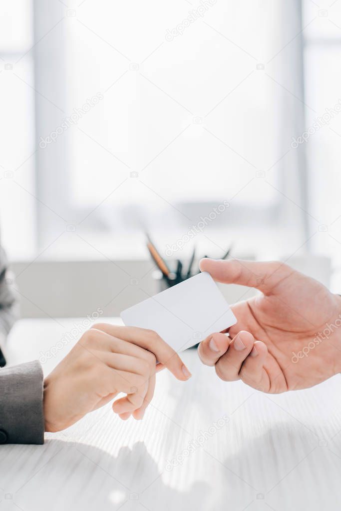 cropped image of patient giving business card to doctor in clinic