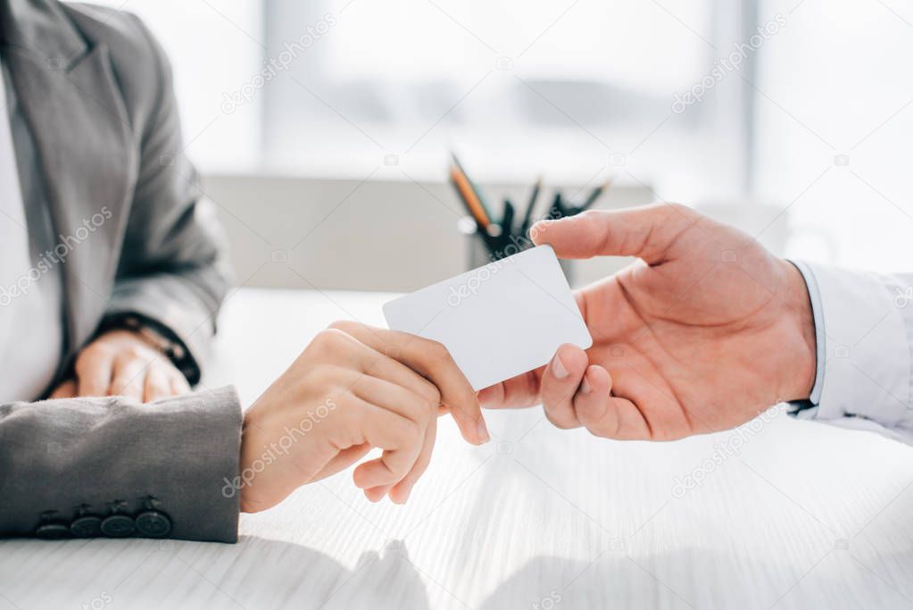 cropped image of patient giving id card to doctor in clinic