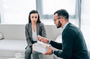 psikolog doktor ofisinde üzgün ağlayan hasta peçete veren