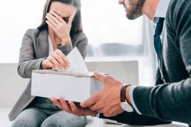 psikolog doktor ofisinde ağlayan hasta peçete vererek resim kırpılmış