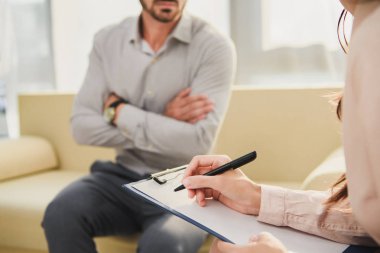 cropped view of patient and psychologist writing diagnosis in clipboard in office clipart