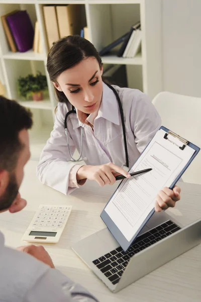 Female Doctor Showing Insurance Claim Form Man Office — Stock Photo, Image