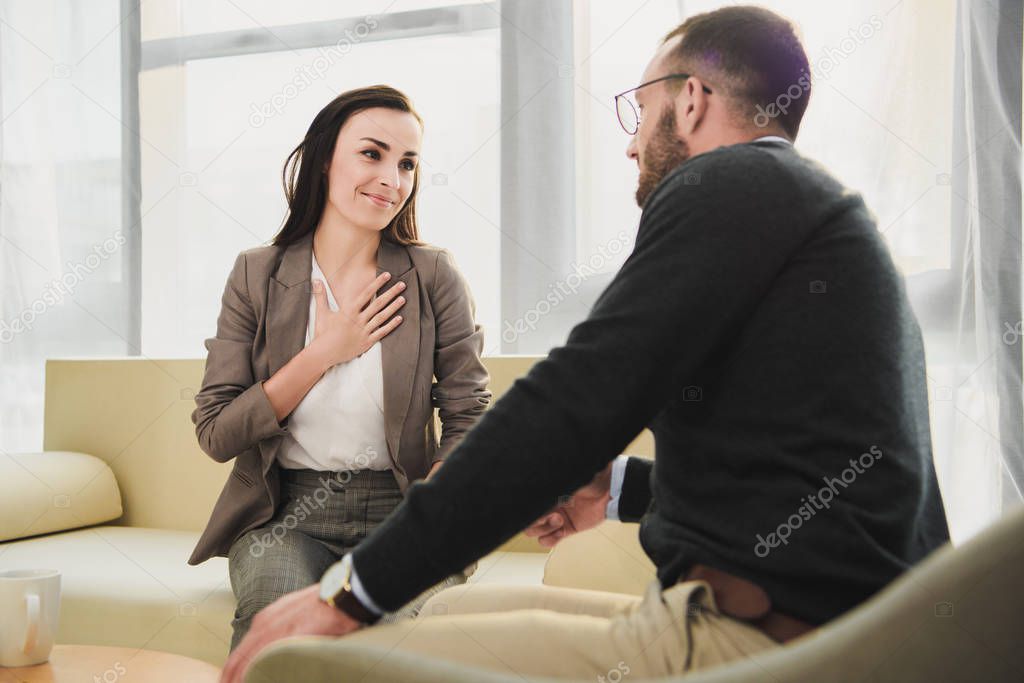 happy patient touching chest in psychologist office