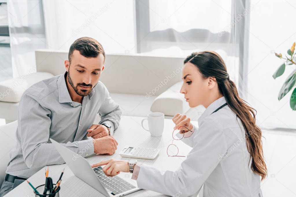 female doctor showing something on laptop to client in office