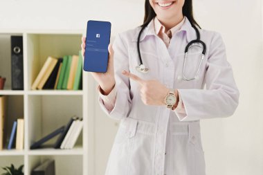smartphone ile facebook app işaret stetoskop ile doktor görünümünü kırpılmış