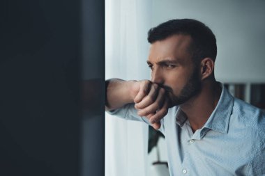 upset pensive man looking at window at home clipart