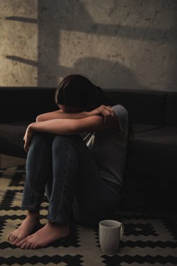 duygusal Ağlayan kadın kanepe katında otururken dizleri sarılma